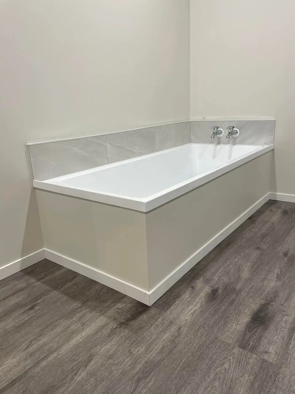 New built-in bath with tiled splashback and vinyl flooring