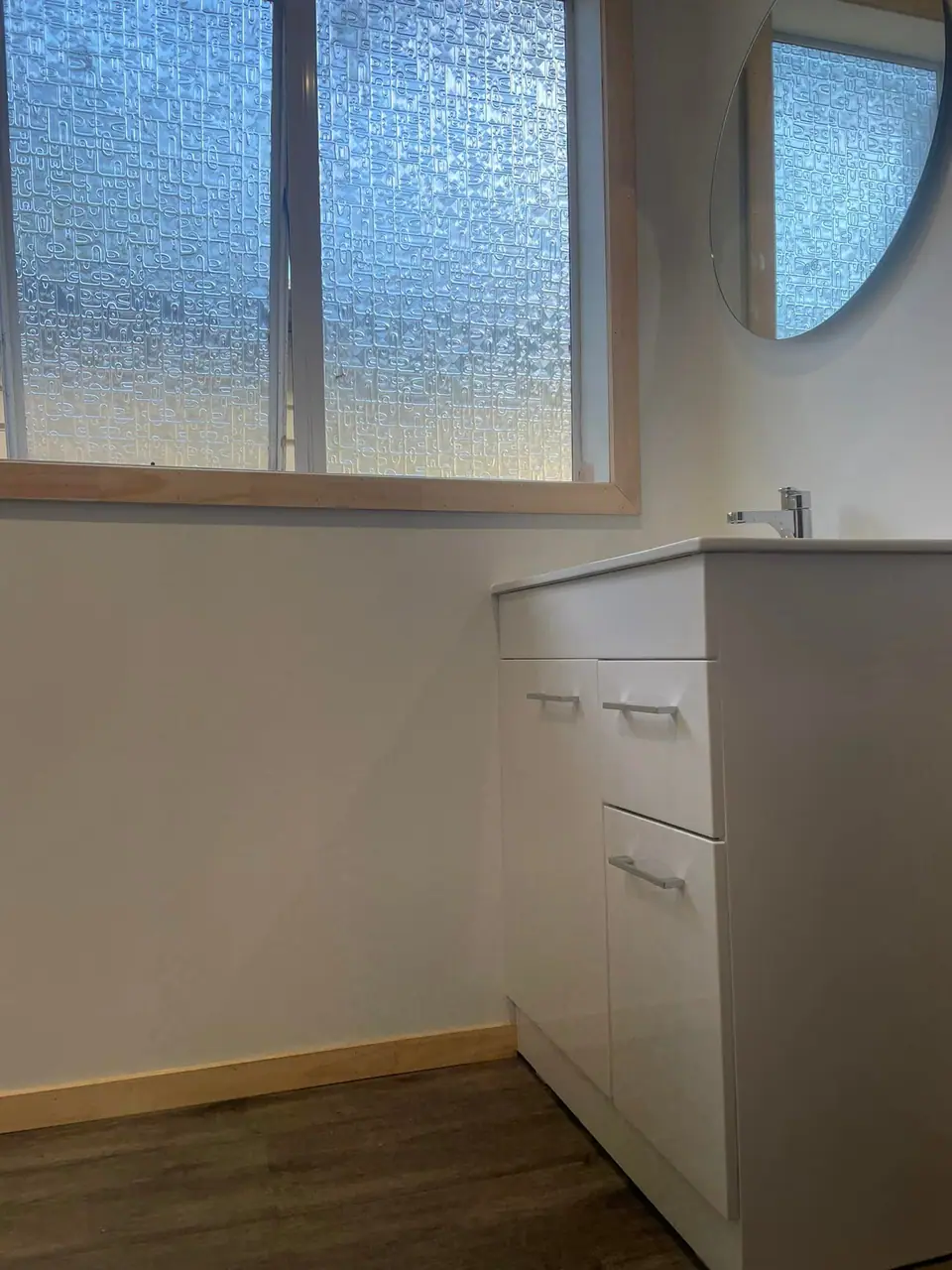 Bright bathroom with new white vanity and frosted window