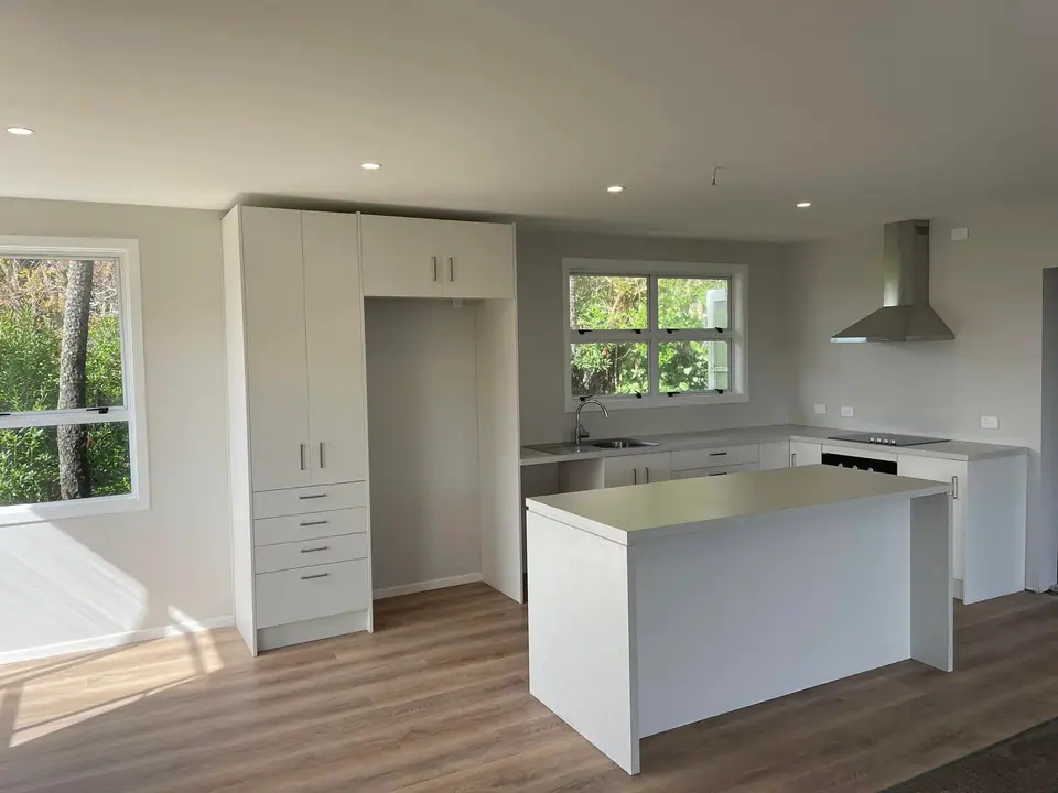 Finished kitchen with island bench, tall pantry cabinets and timber-look flooring