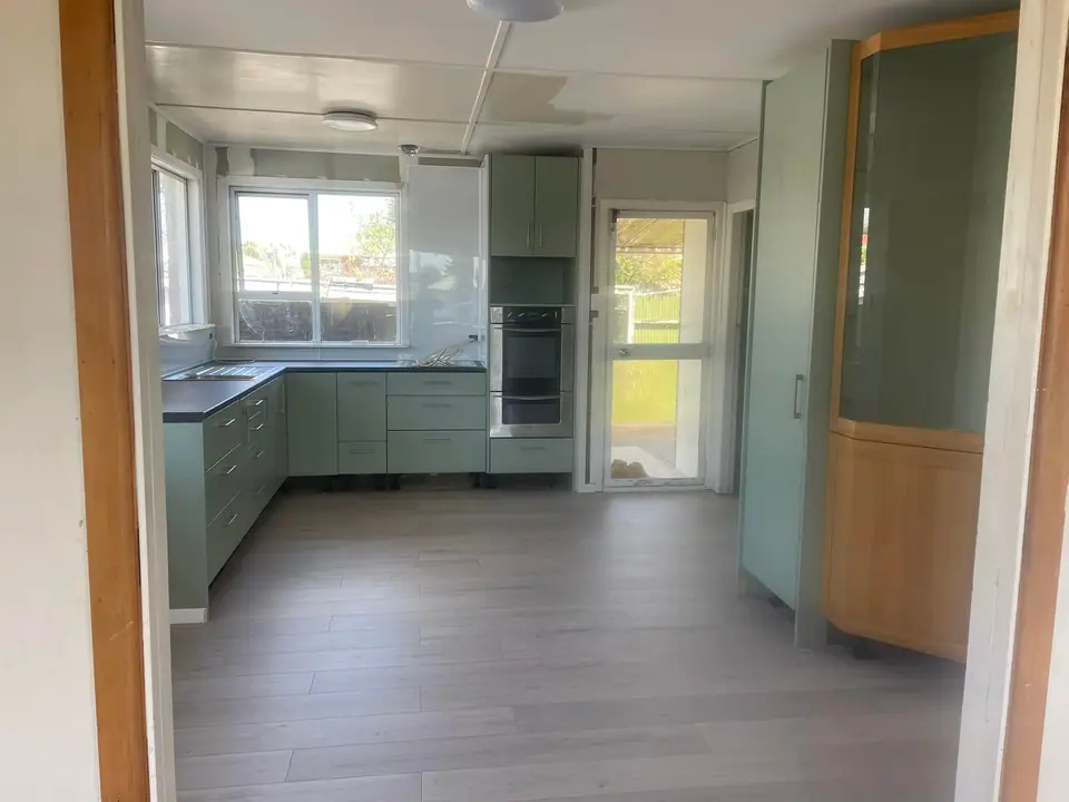 Renovated kitchen with sage green cabinetry and new vinyl flooring