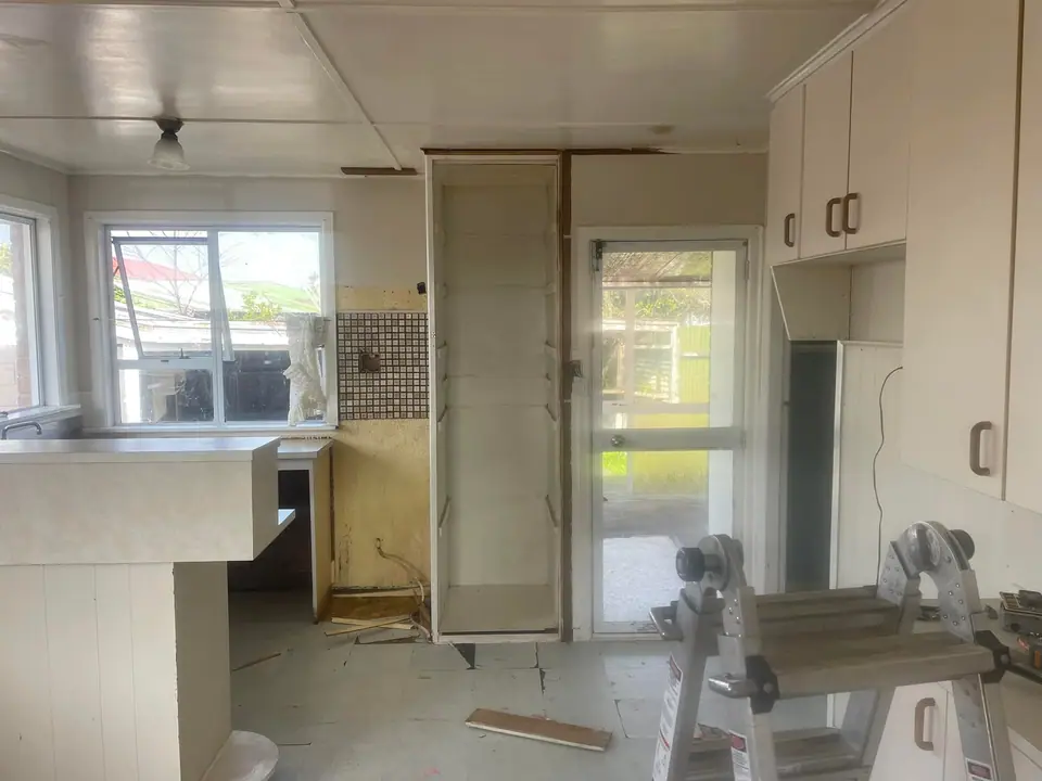 Kitchen mid-renovation with old cabinetry removed and walls opened up