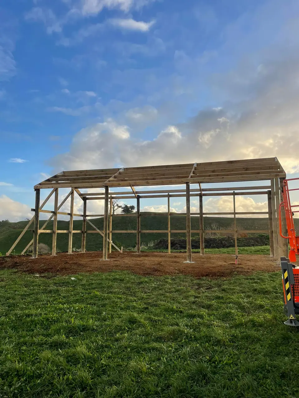 Pole shed frame on farmland under a blue sky