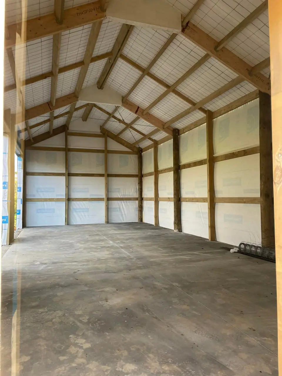 Pole frame shed interior with timber trusses and clear roof panels